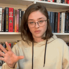 a woman wearing glasses stands in front of a shelf full of books one of which is titled " vampiros "