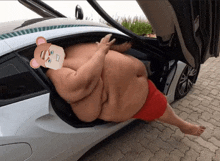 a sumo wrestler is sitting in the back of a car with the trunk open