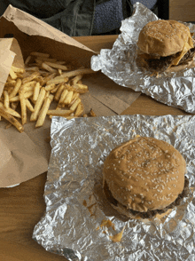 two hamburgers and a bag of french fries on a table