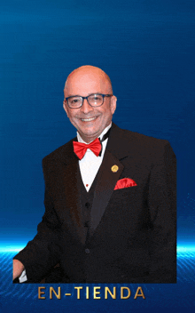 a man in a tuxedo and bow tie stands in front of a blue background that says en-tienda on it