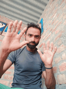 a man with a beard holds his hands up in front of his face