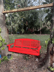 a red porch swing is hanging from a tree