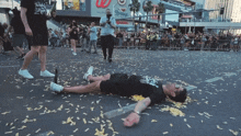 a man is laying on the ground in front of a crowd with a sign that says ' ucsd ' on it