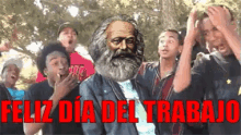 a group of people are standing around a man with a beard and the words feliz dia del trabajo in red