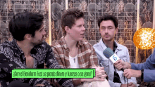 a group of men are sitting in front of a microphone with a green sign that says con el benidorm fest