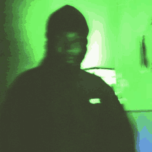 a shadow of a man in a black hoodie is against a green wall .