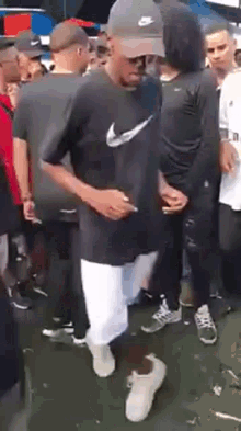 a man in a nike shirt is dancing in a crowd .