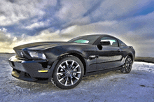 a black mustang is parked in the snow with the number 50 on the side