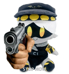 a person is holding a gun in front of a stuffed animal that says stop now .