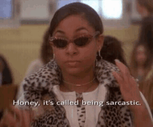 a woman wearing sunglasses and a leopard print vest is saying `` honey , it 's called being sarcastic '' .