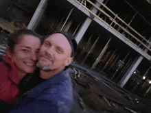 a man and a woman are posing for a photo in front of a building under construction