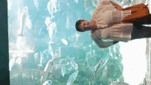 a woman is standing in front of a large aquarium full of fish