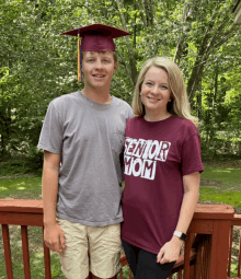 a woman wearing a maroon shirt that says senior mom stands next to a boy in a graduation cap