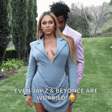 a woman in a blue dress stands next to a man in a pink suit