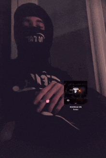 a man wearing a black hoodie and a black face mask is listening to a song called " nouvelle vie "