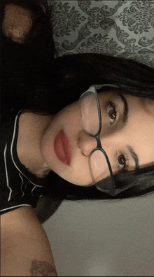 a woman wearing glasses and red lipstick takes a picture of herself