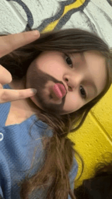 a little girl with a beard on her face is making a funny face