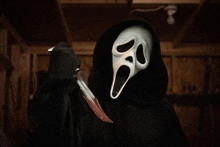 a person with a scream mask holding a bloody knife