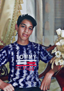 a young boy wearing a tommy hilfiger shirt sits on a couch