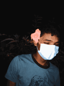 a young man wearing a face mask has a flower on his ear