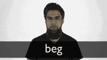 a man with glasses and a beard is wearing a black shirt with the word beg below him