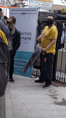 a man wearing a yellow shirt stands in front of a banner that says partido libertario