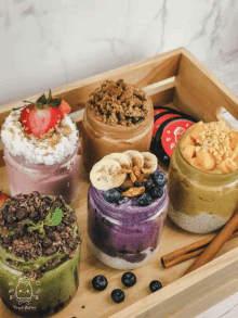 a wooden tray holds a variety of desserts including a strawberry banana and blueberry dessert