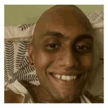 a man with a shaved head is smiling and looking at the camera