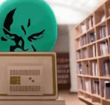 a green ball is sitting on top of a laptop computer in a library .