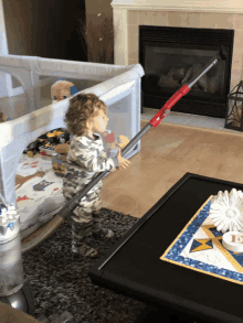 a little boy is holding a vacuum cleaner in his hand