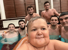 a group of men are taking a picture of a baby in a bath tub