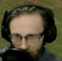 a man wearing headphones and glasses is speaking into a microphone .