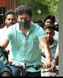 a man wearing a mask is riding a bike in a crowd