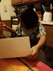 a little girl sitting at a table holding a piece of paper that says " i love you " on it