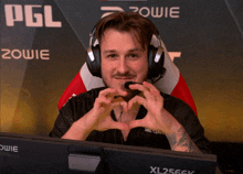 a man sitting in front of a xl2566k monitor making a heart shape with his hands