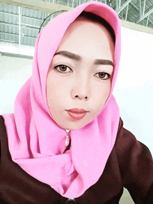 a woman wearing a pink hijab and a brown shirt