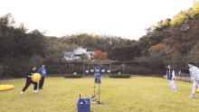 a group of people are playing a game of frisbee in a field with a blue bucket in the middle of the field