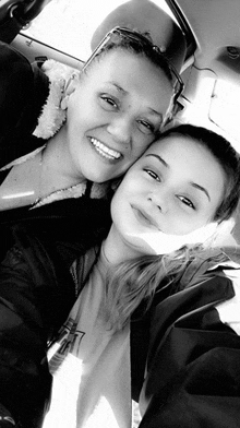 two women are posing for a picture in a car and smiling .