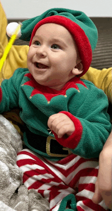 a baby dressed in an elf costume is smiling for the camera