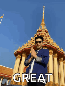 a man in a blue jacket stands in front of a temple with the words great behind him