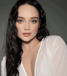 a woman with long dark hair is wearing a white shirt with a plunging neckline