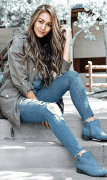 a woman is sitting on a set of stairs wearing ripped jeans and blue boots