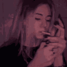 a woman is smoking a cigarette in a dark room while looking at her phone .