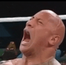 a bald man is screaming in a boxing ring with his mouth open .