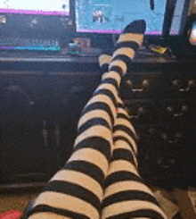 a person wearing black and white striped socks is sitting in front of a computer monitor .