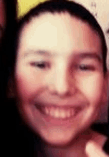 a close up of a young boy 's face smiling and wearing a yellow headband .