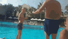 a man and a boy are standing in a swimming pool .