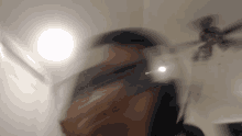 a blurry picture of a person 's face with a ceiling fan behind them