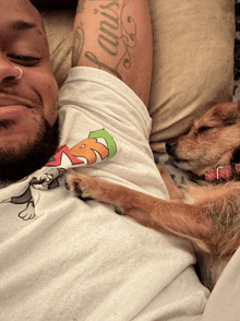 a man with a tattoo on his arm has a dog sleeping on his shoulder