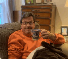 a man is sitting in a chair holding a mug that says ohama city beach